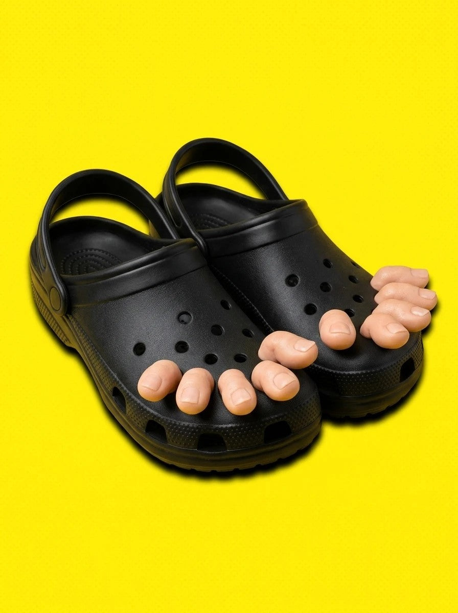 Black clogs with toe charms on a yellow background